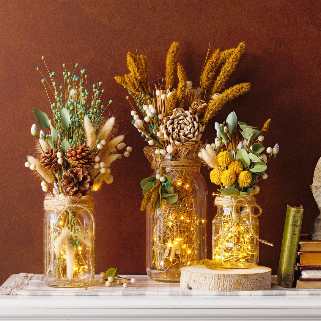 Rustic wedding centerpiece with mason jars, fairy lights, and dried flowers on a decorated reception table