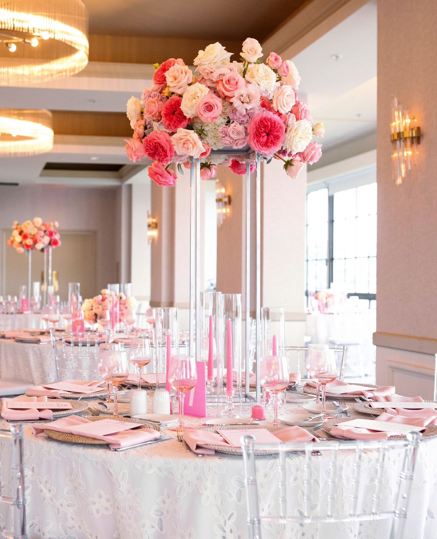 Tall pink and blush floral wedding centerpiece with candles on an elegant indoor reception table